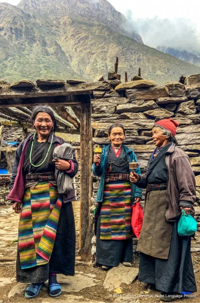 Three women standing in front of a typical home in the main path that runs through Sama village (3550m). They are wearing the typical Tibetan-style Nubri dress that most women over about 30 wear. They are on their way to the eye screening clinic.  