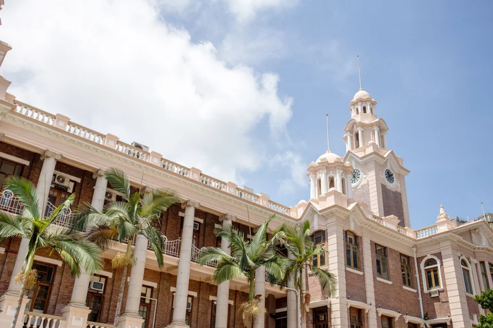 Historic HKU building with classical architecture, palm trees, and a clear blue sky.