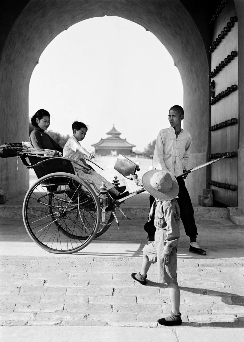 Bag being passed to a mother and child in a rickshaw.